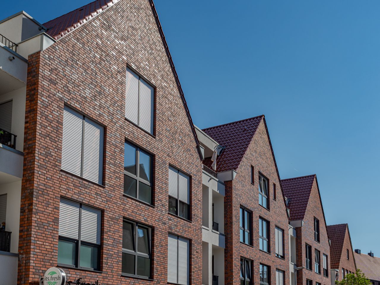 Contemporary brick apartment buildings under a clear blue sky in Coesfeld, Germany.